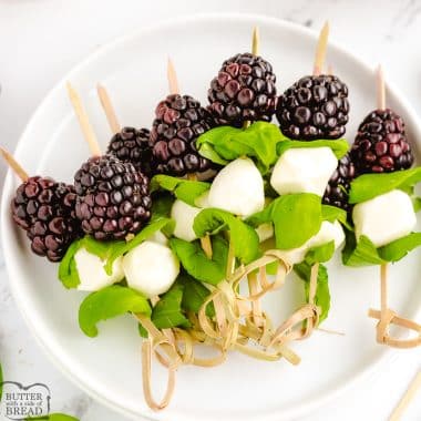 blackberry caprese pops appetizers on wooden skewers on a plate