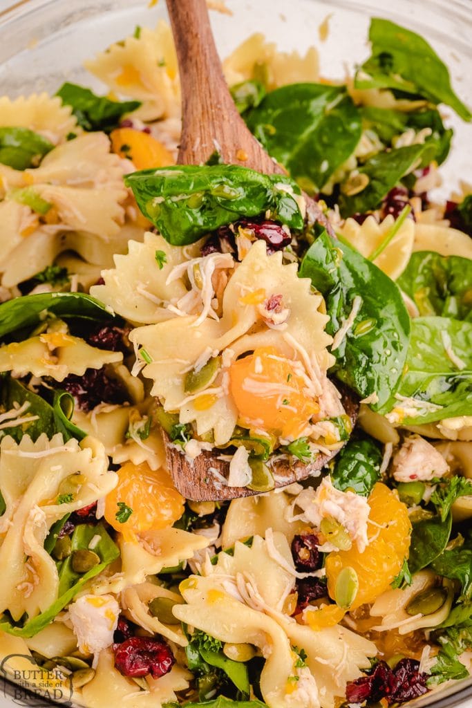 bowl full of pasta salad with spinach, chicken, mandarin oranges, craisins