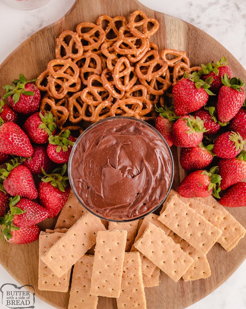 chocolate peanut butter dip with yogurt arranged with fruit and pretzels around the tray