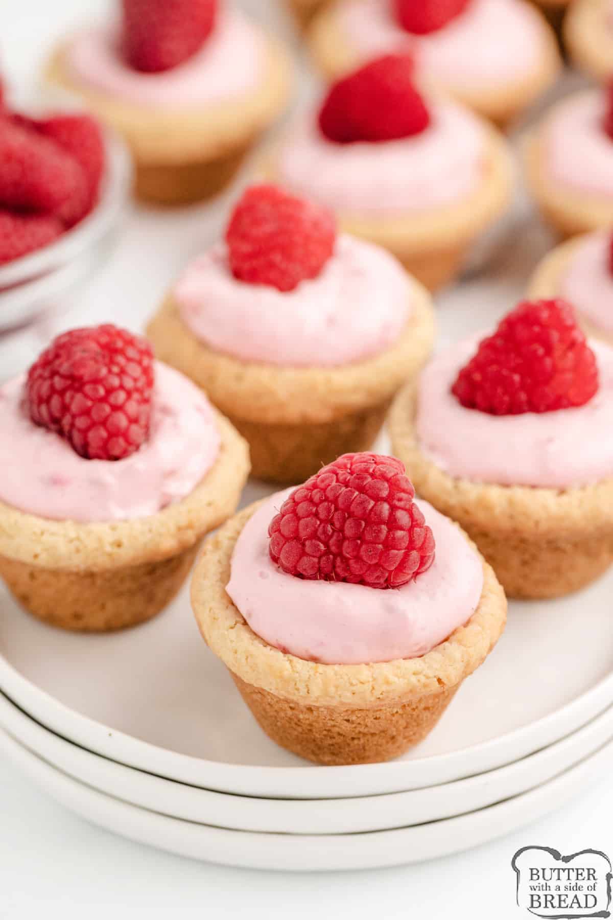 Raspberry Cheesecake Cookie Cups are made with a sugar cookie recipe that is filled with a raspberry cream cheese filling. These delicious raspberry cookie cups are so simple to make! 