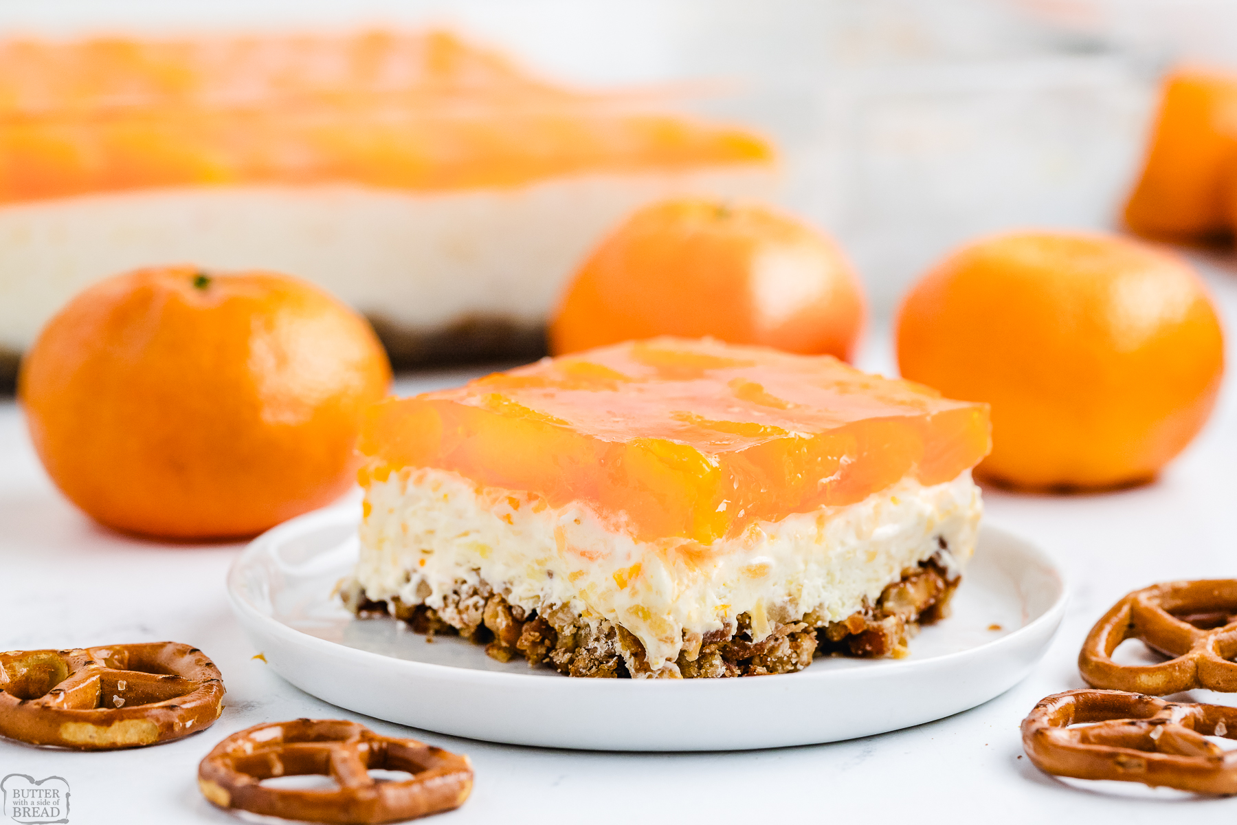 Tropical Jello Pretzel Salad made with a pineapple coconut cream mixture & mandarin orange jello, all atop a buttery pretzel crust!