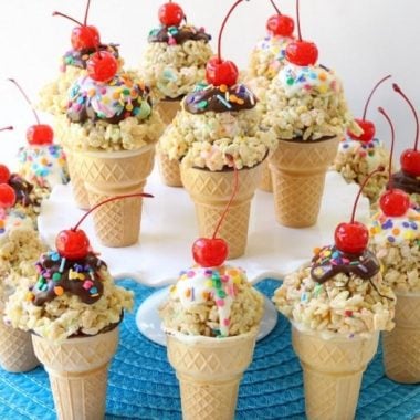 Rice Krispie Ice Cream Cones are easy to make & super cute too! Gooey marshmallow treats topped with melted chocolate, sprinkles & a cherry make these cute cones amazing. Bonus too- they each have a special treat inside the cone!