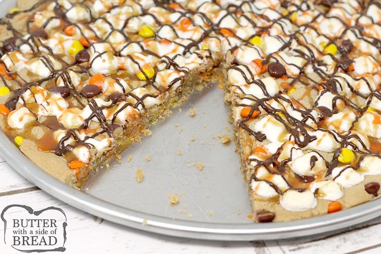 Halloween Peanut Butter Cookie Pizza is made with a delicious peanut butter cookie crust that is topped with marshmallows and Reese's Pieces and then drizzled with chocolate, caramel and orange icing! The perfect Halloween dessert!