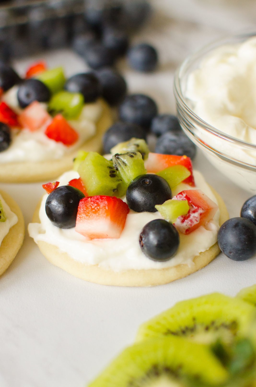 Fruit Pizza Cookies are all the goodness you get in a fruit pizza individualized! Soft crust, vanilla whipped cream frosting, topped with your favorite fruits; strawberries, raspberries, blueberries, kiwi, blackberries, mango.. the possibilities are endless! 