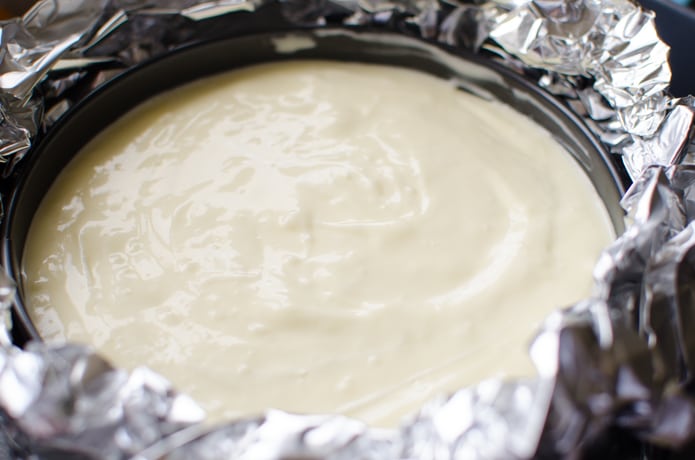 Cheesecake in the springform pan, the bottom covered with tinfoil, ready to go into the water bath and oven.