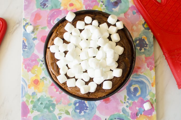 Marshmallows onto of the chocolate cheesecake before being broiled in the oven.