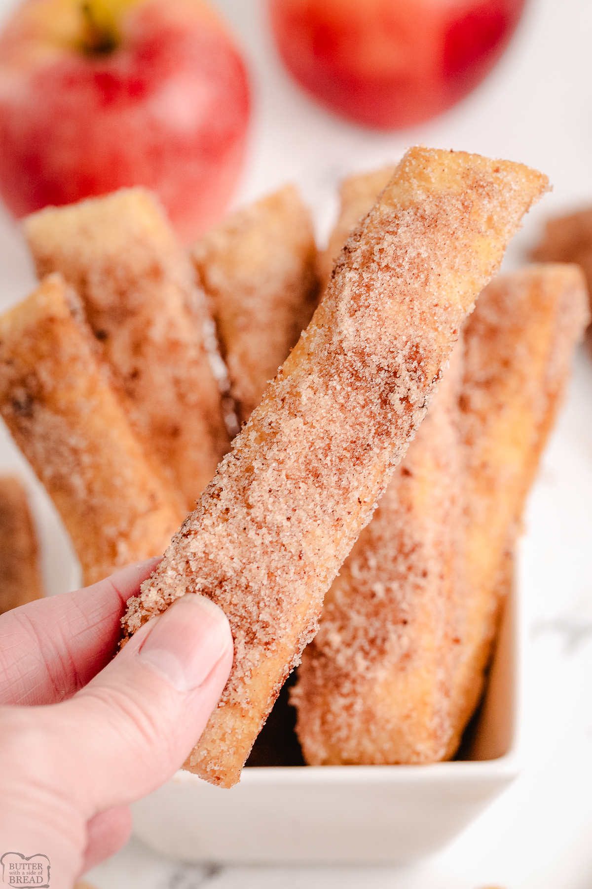 holding a crispy cinnamon sugar apple fry