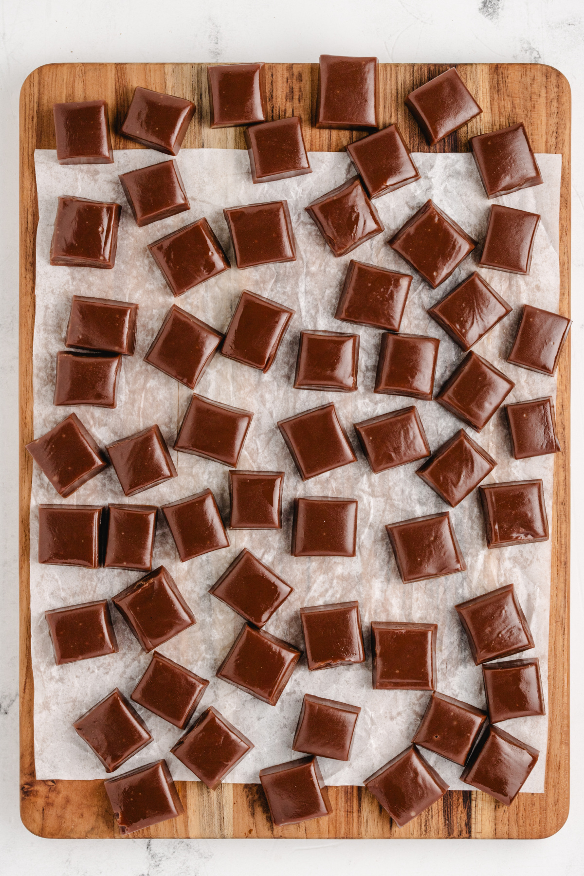 Soft chocolate caramel squares arranged on parchment paper.