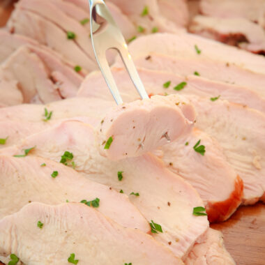 meat fork with a piece of smoked turkey on a platter
