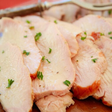 juicy slices of smoked turkey on a wooden platter