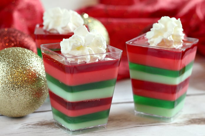 Layered Christmas Jello cups are fun, festive and easy to make for holiday parties! This layered Jello recipe is made with cherry and lime gelatin for a delicious flavor combination in the perfect colors for Christmas!