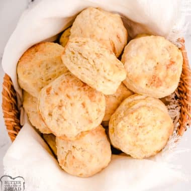 buttery flaky homemade biscuits in a basket with a white cloth