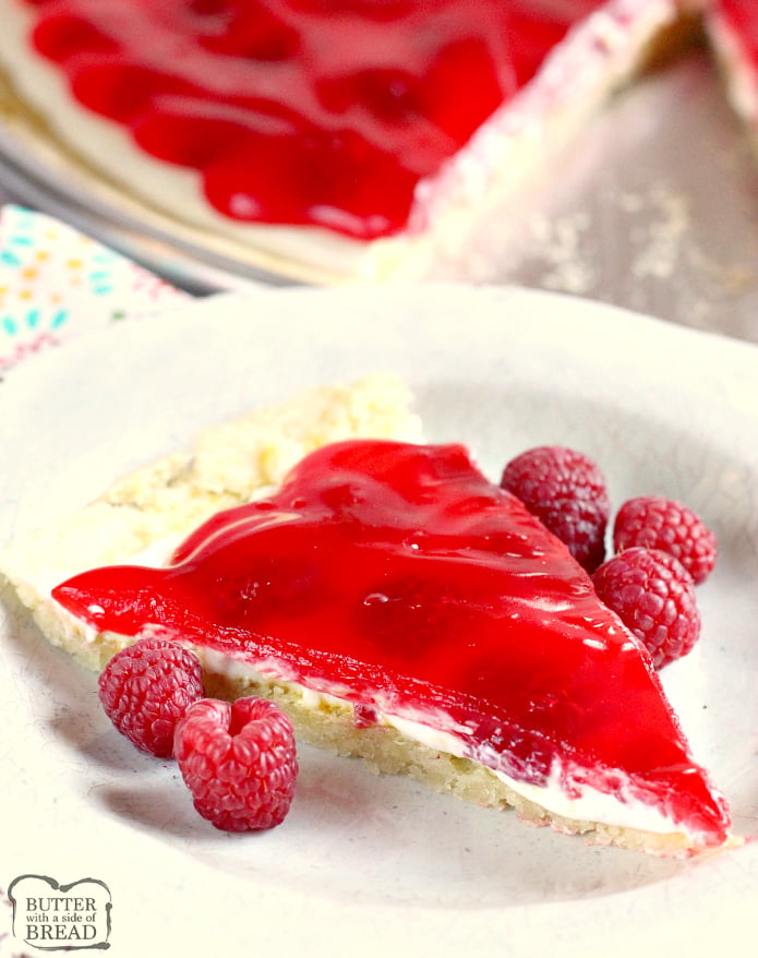 Lemon Raspberry Fruit Pizza is made with a lemon sugar cookie crust that is topped with a cream cheese layer, fresh raspberries and a delicious raspberry glaze! This fruit pizza recipe is so easy to make by using a lemon cookie mix and the glaze is made with raspberry jello!