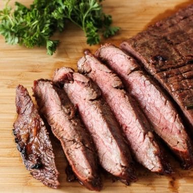 sliced grilled flank steak on a wooden cutting board