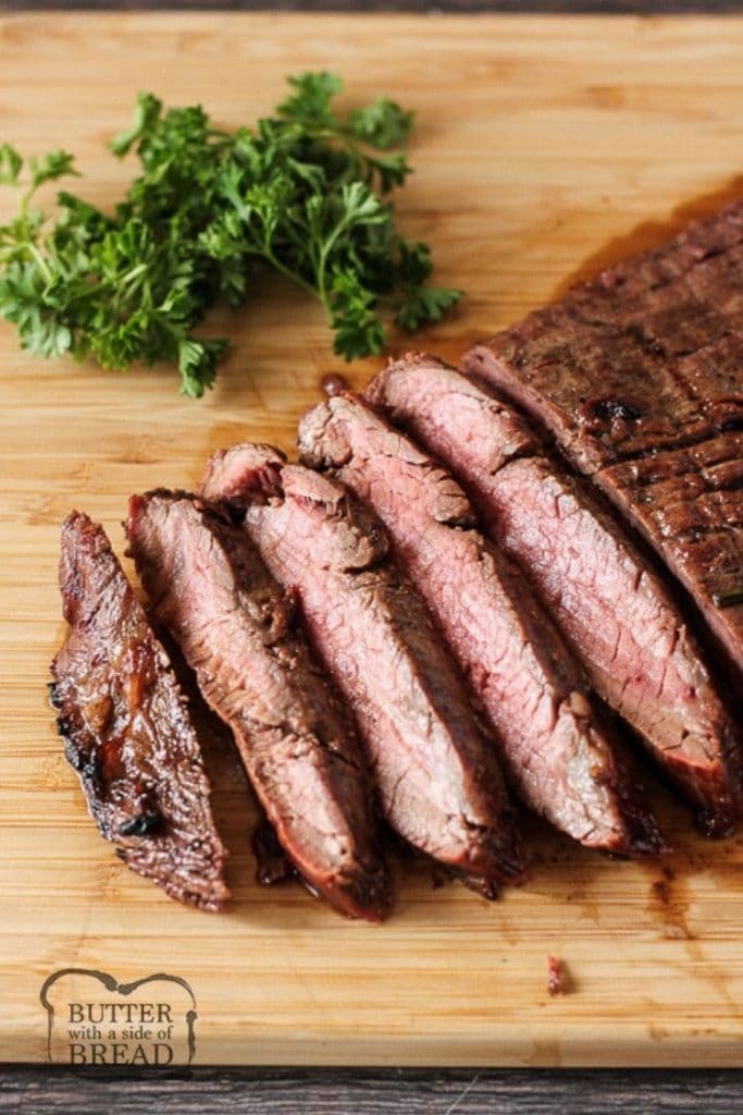 sliced grilled flank steak on a wooden cutting board
