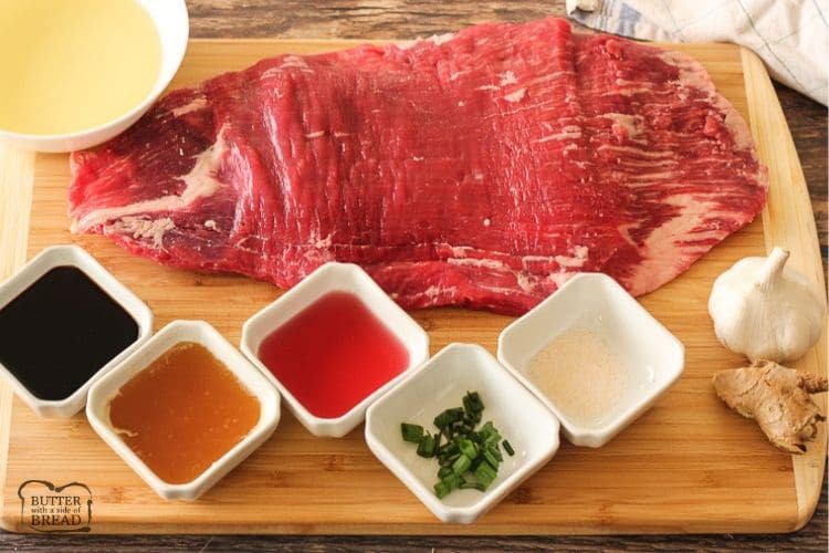 flank steak surrounded by marinade ingredients in white bowls