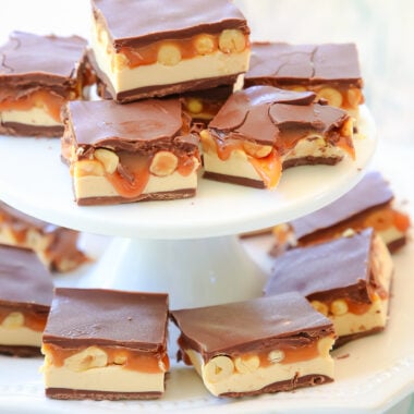 stack of homemade snickers bars on a white pedestal