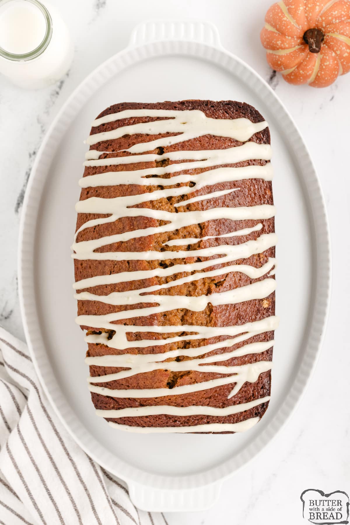 Loaf of pumpkin bread with cream cheese glaze drizzled on top.