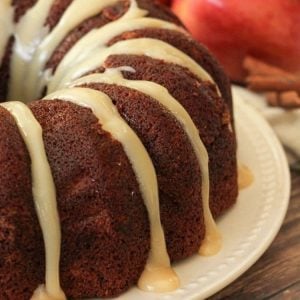 apple spice cake with caramel frosting on a white plate