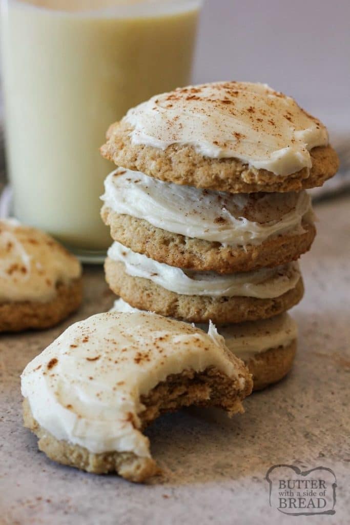 pile of eggnog cookies with a glass of eggnog in the background