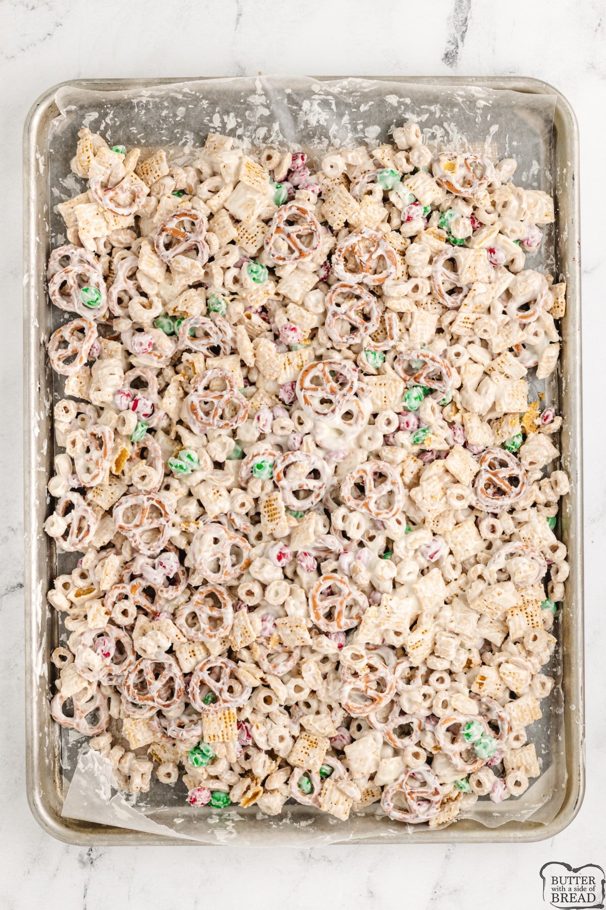 Spreading party mix on a baking sheet with wax paper to set up. 