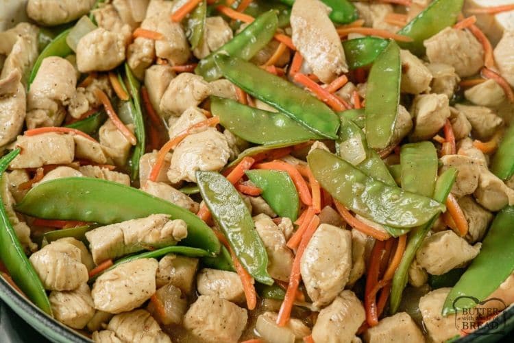 cashew chicken, snow peas and carrots in a pan