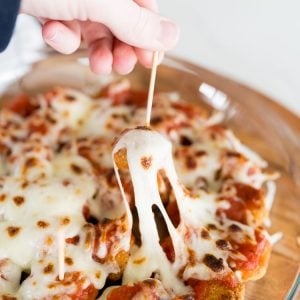 chicken parmesan bites appetizer, with a toothpick and cheese pulling