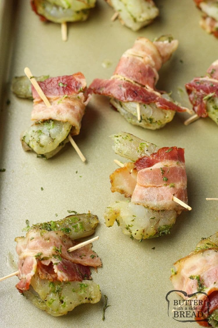 bacon wrapped shrimp uncooked on a baking sheet.
