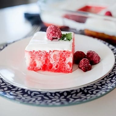 Raspberry Jello Poke Cake is a simple yet flavorful cake recipe. White cake infused with raspberry jello topped with cream to make one memorable, easy poke cake!