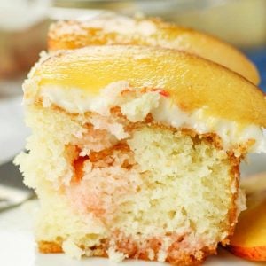 slice of peach poke cake topped with fresh peach slices
