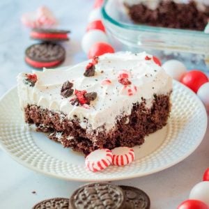 Peppermint Oreo Poke Cake uses a cake mix, cookies & cream pudding, whipped cream, Oreos & peppermint candies for a deliciously festive holiday cake! Easy Christmas cake recipe with peppermint cookie flavors.