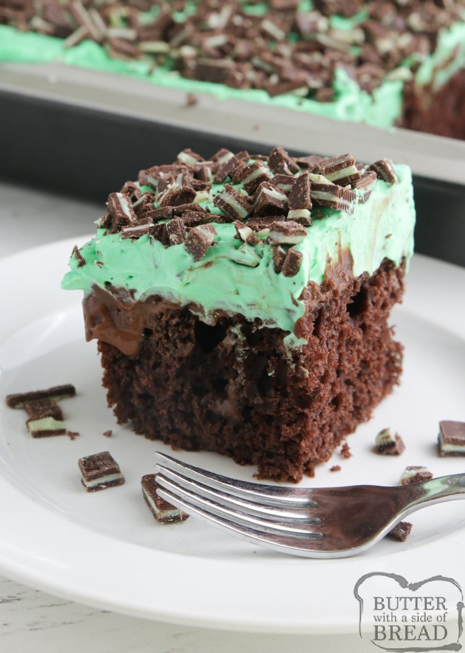 Mint Chocolate Poke Cake made with a cake mix, hot fudge, chocolate pudding and a mint flavored whipped cream topped with chopped Andes mints. Decadent but easy chocolate cake recipe!