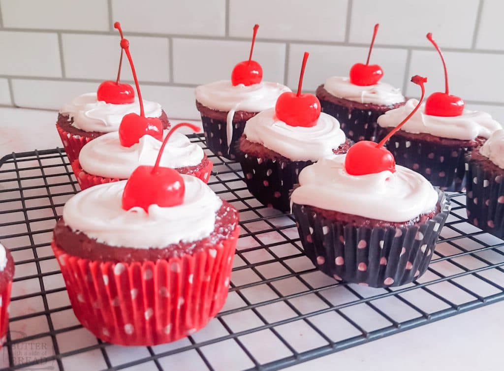 cherry cola cupcakes with white frosting and a cherry on top