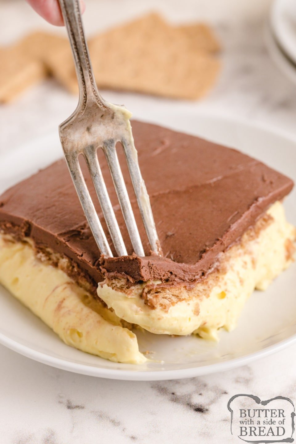 No Bake Eclair Cake made with graham crackers, vanilla pudding and a delicious fudgy chocolate frosting layer on top. This no bake chocolate eclair dessert tastes just like a cream puff!
