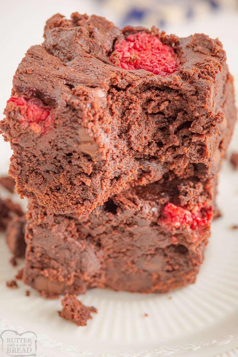 two squares of thick raspberry chocolate brownies stacked with a bite taken out of one
