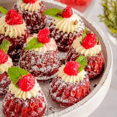 red velvet mini bundt cakes topped with cream cheese frosting and raspberries