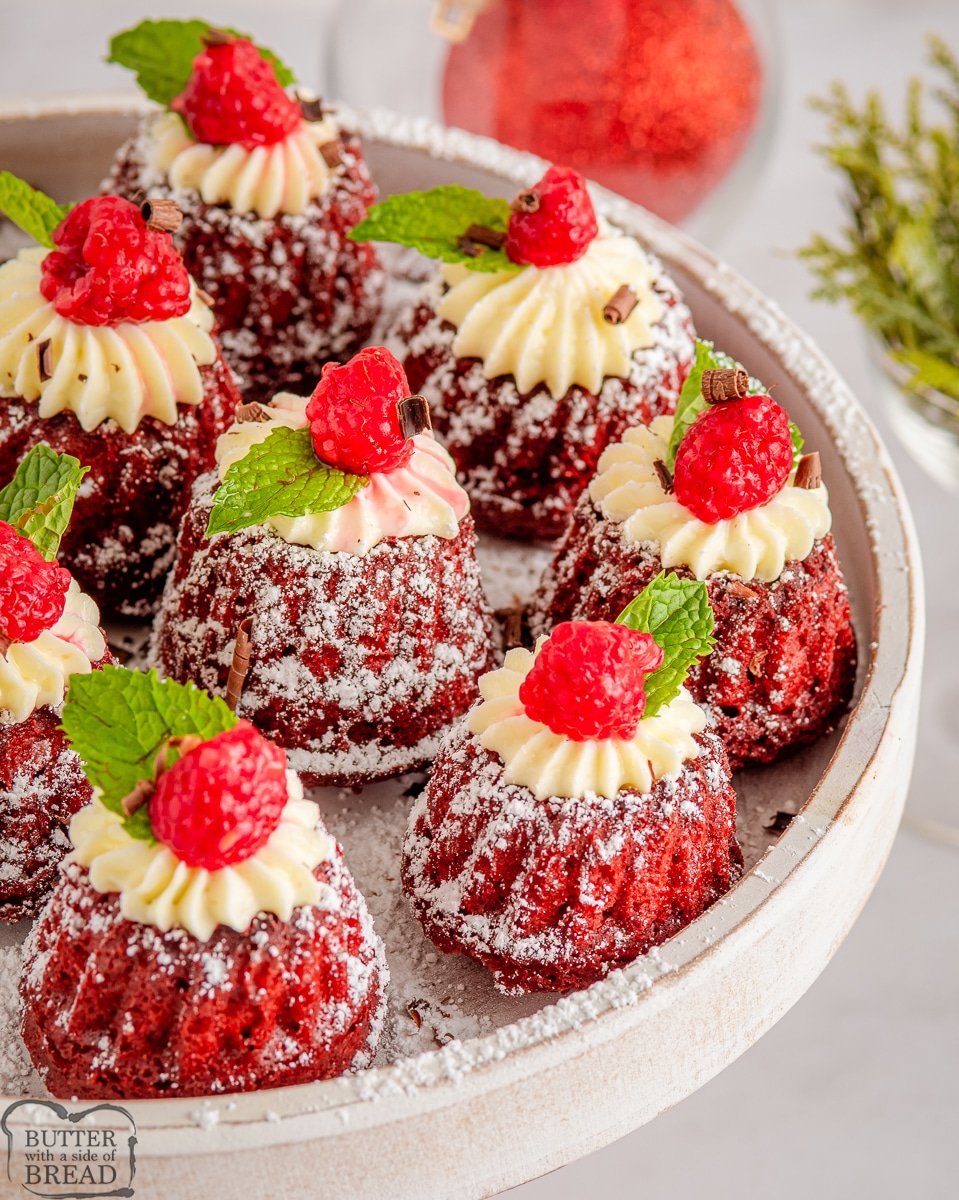 red velvet mini bundt cakes topped with cream cheese frosting and raspberries