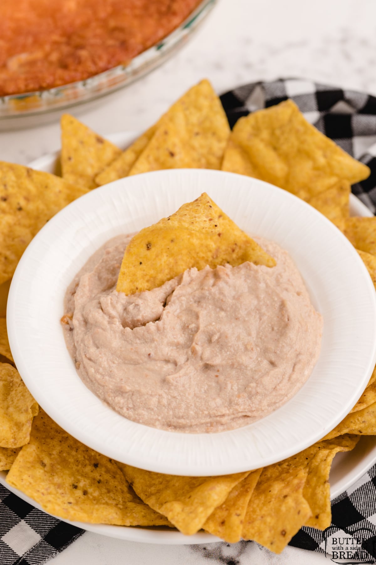 Chip dip made with refried beans, cream cheese, sour cream, green salsa and cheddar