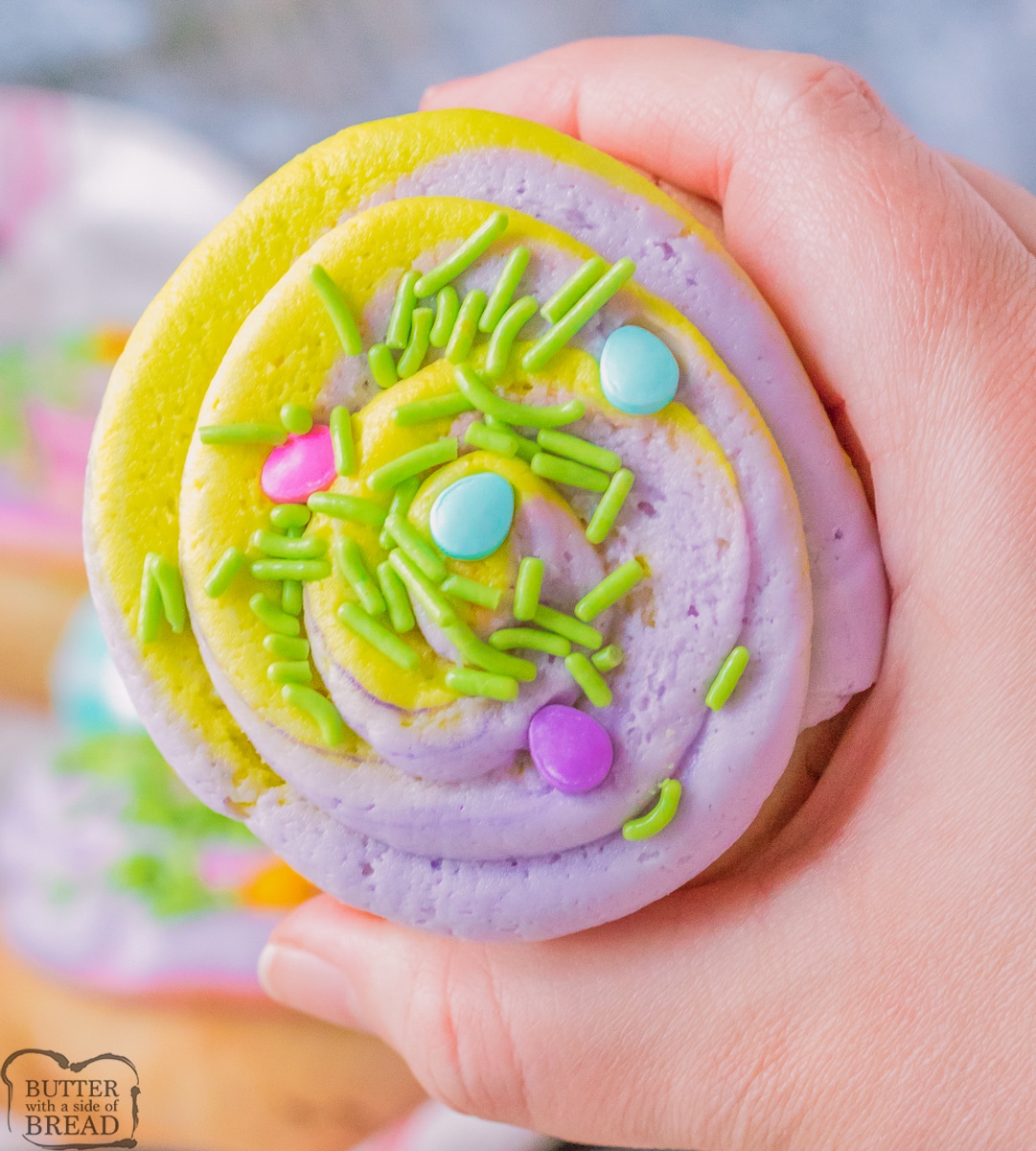 holding a frosted lemon sugar cookie with Spring colored frosting
