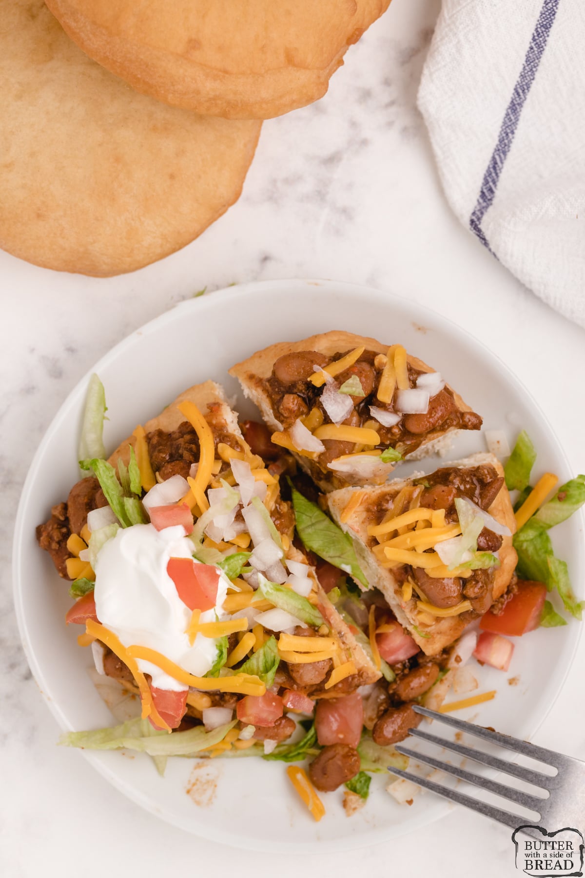 Navajo Tacos topped with chili, cheese, sour cream, lettuce and tomatoes