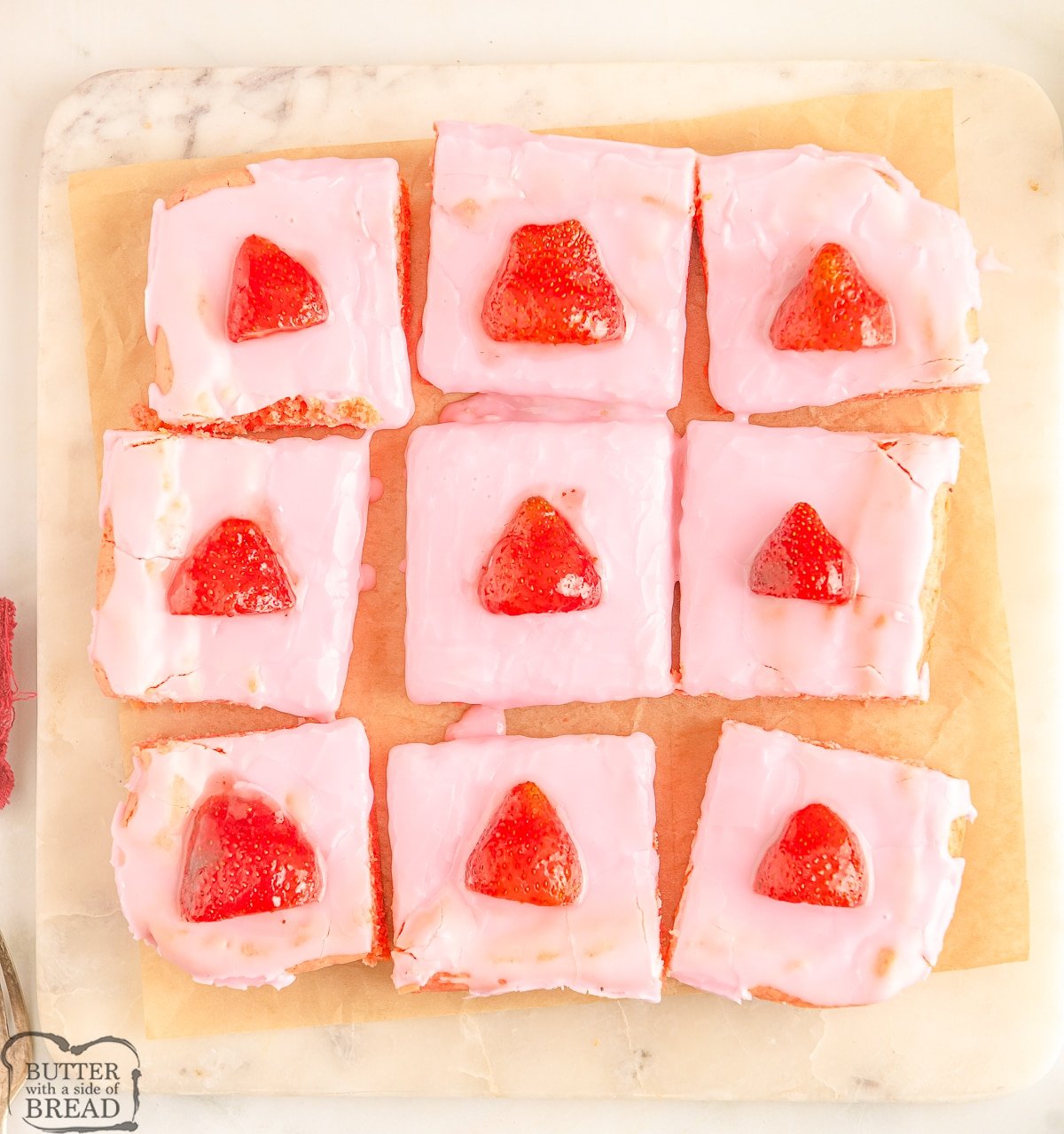 pan of strawberry brownies sliced with fresh strawberries on top