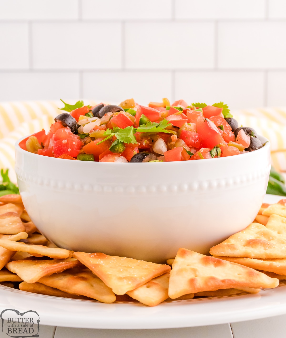 side view of a white bowl filled with salsa with olives