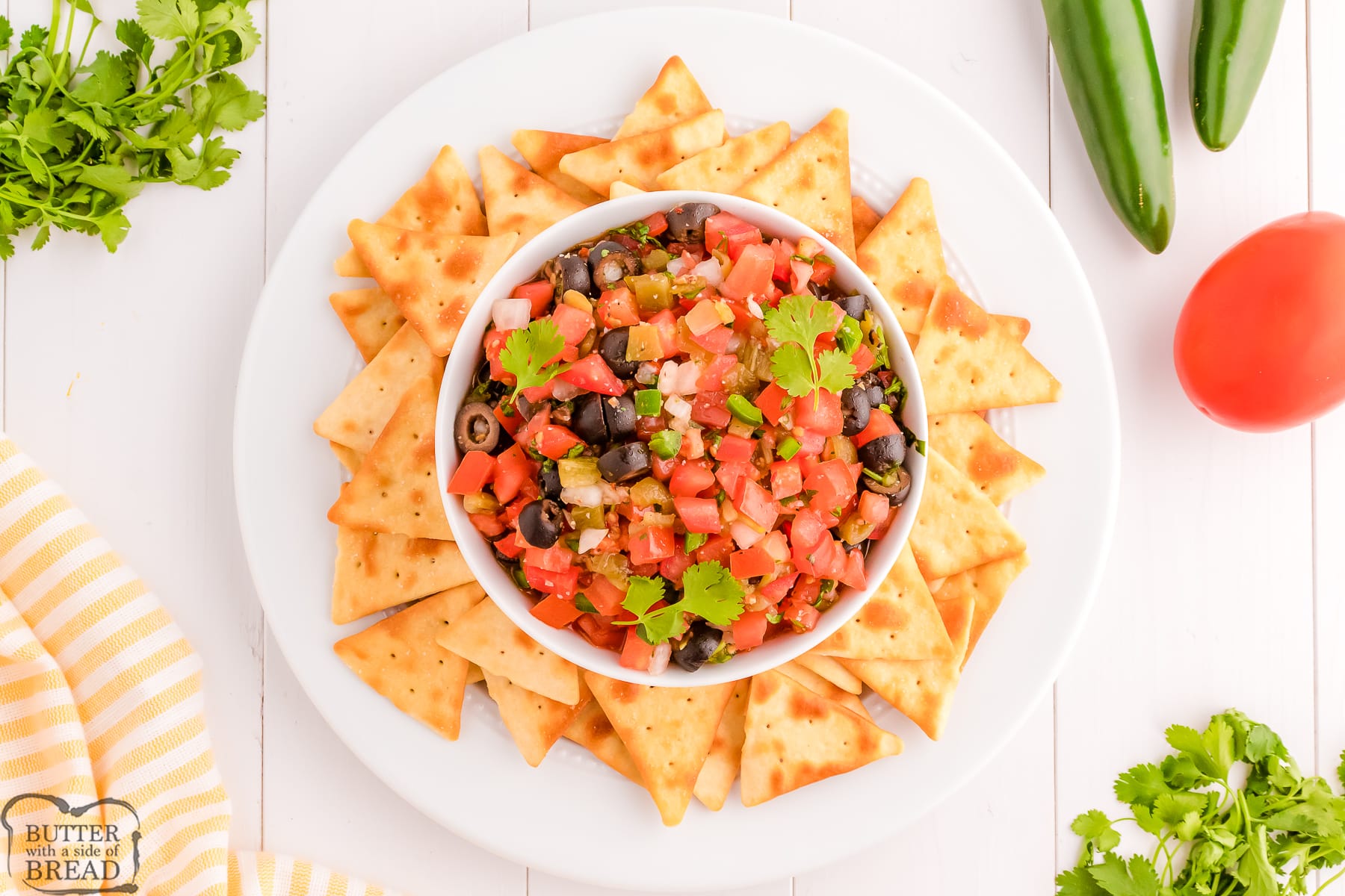 bowl of salsa with olives surrounded by pita chips