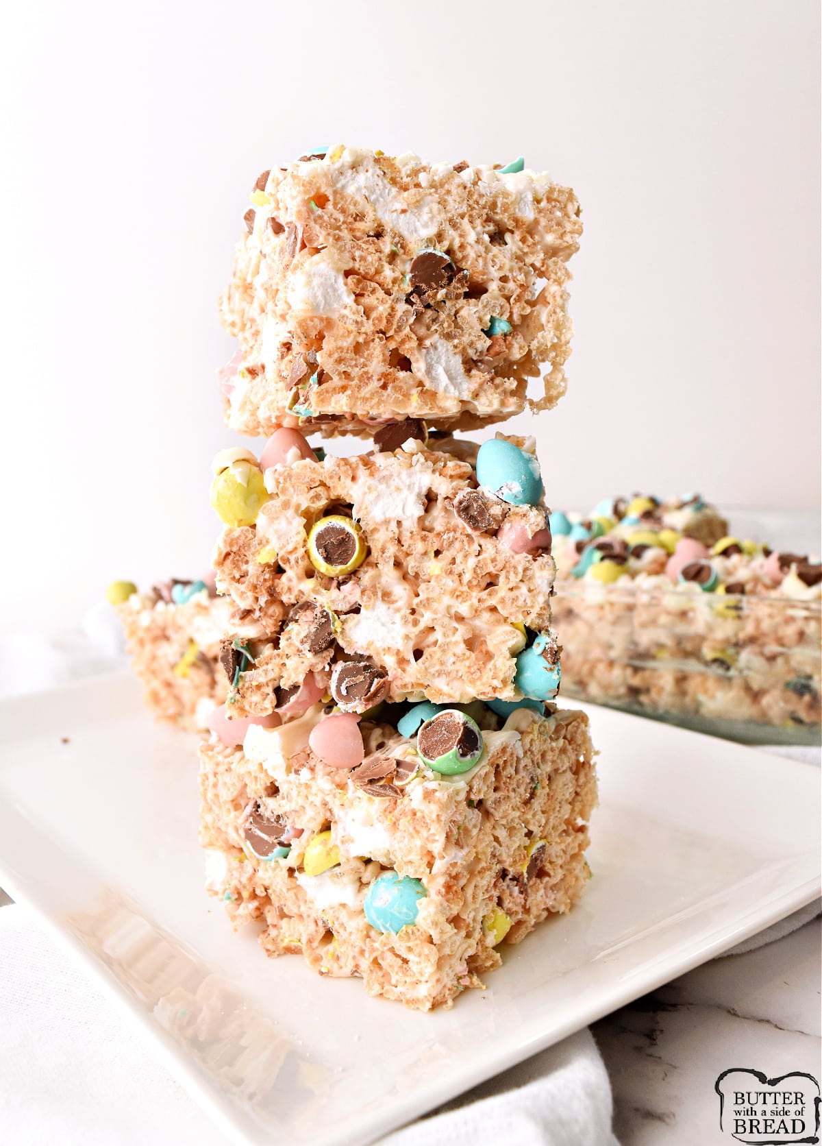 Mini Egg Rice Krispie Treats made with crispy rice cereal, marshmallows, crushed Cadbury mini eggs and topped with a white chocolate drizzle. Rice Krispie Treat recipe that is perfect for Easter and springtime!