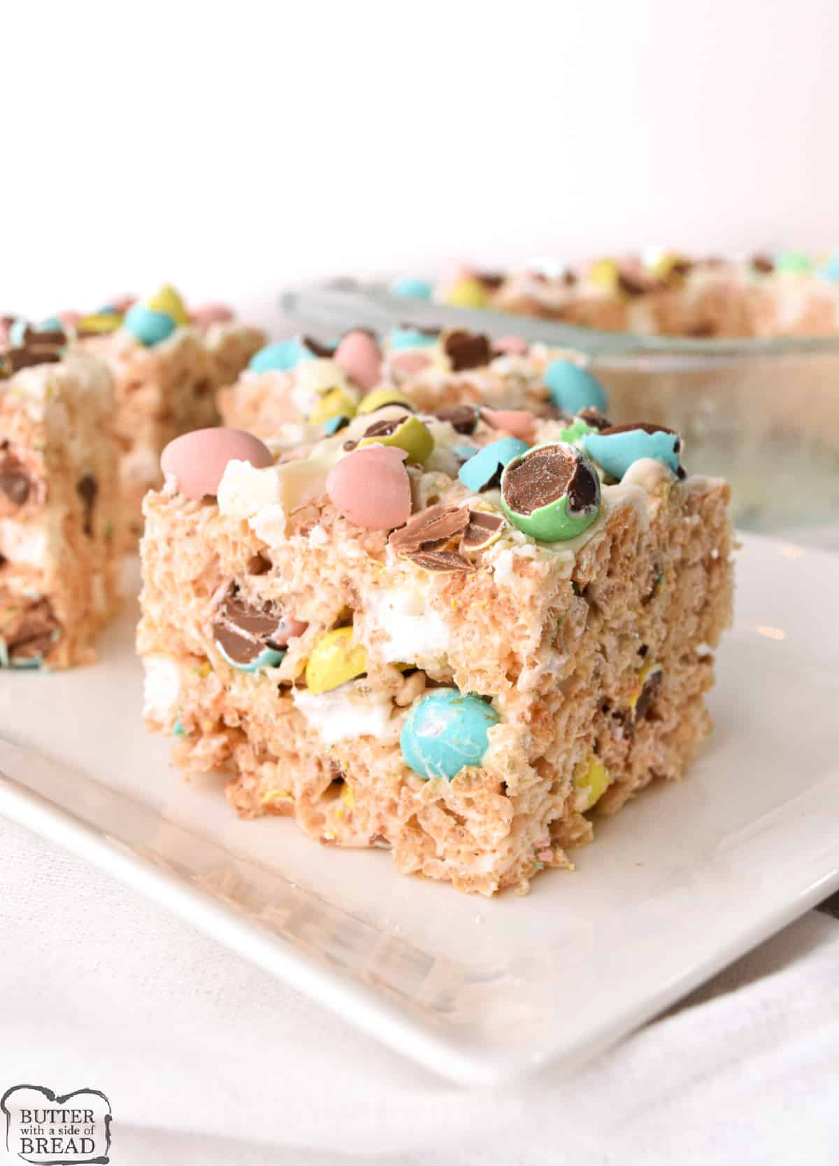 Mini Egg Rice Krispie Treats made with crispy rice cereal, marshmallows, crushed Cadbury mini eggs and topped with a white chocolate drizzle. Rice Krispie Treat recipe that is perfect for Easter and springtime!