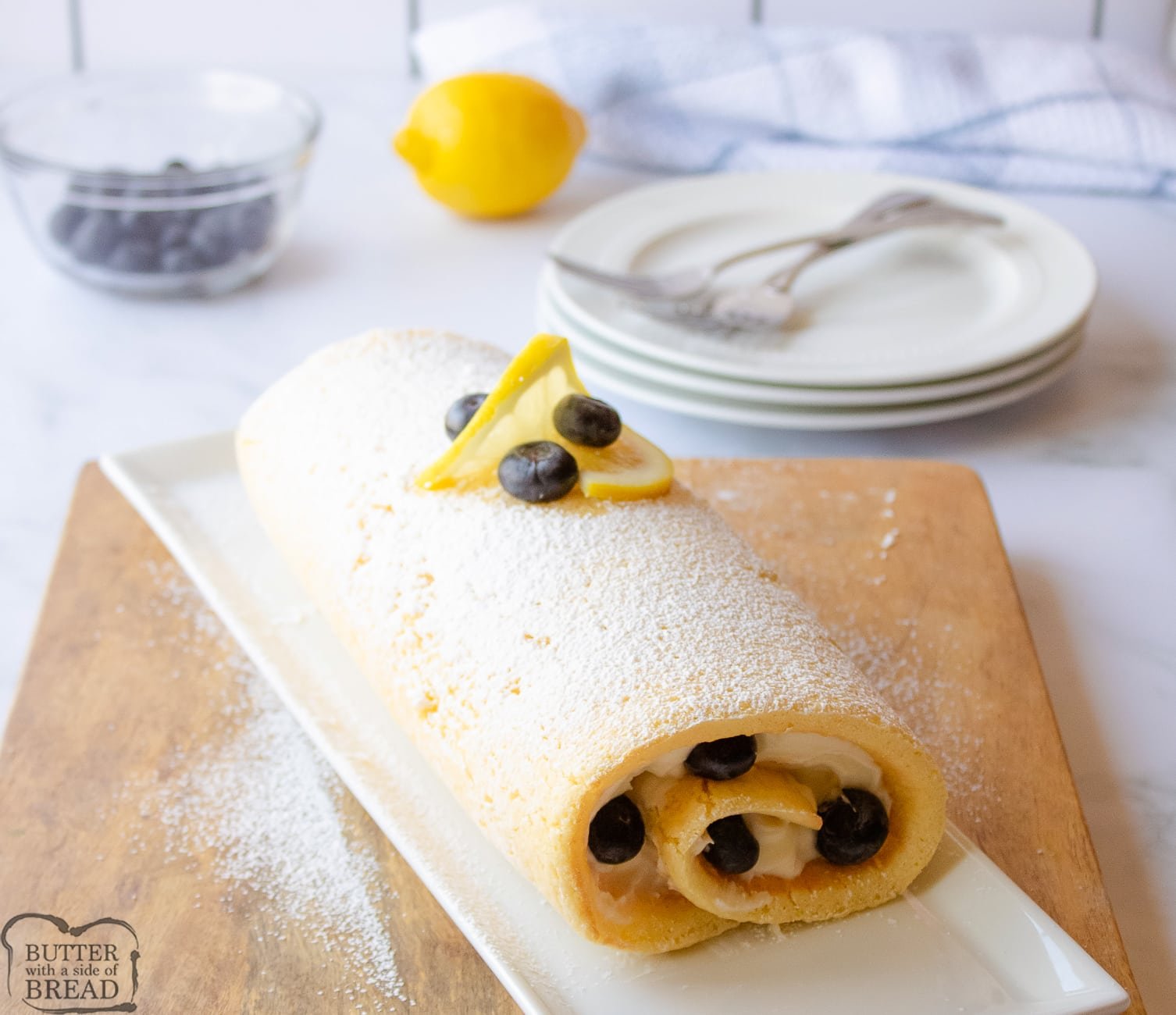 whole lemon cake roll with blueberries on a tray