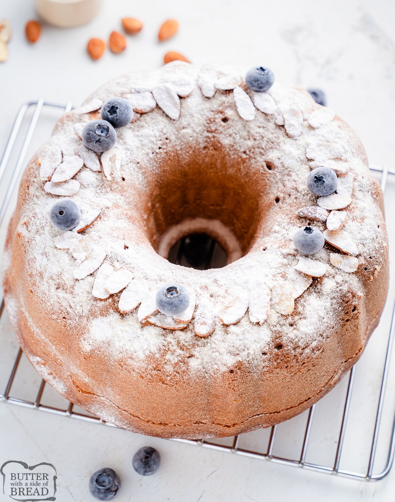 pound cake dusted with powdered sugar and blueberries on a cooling rack