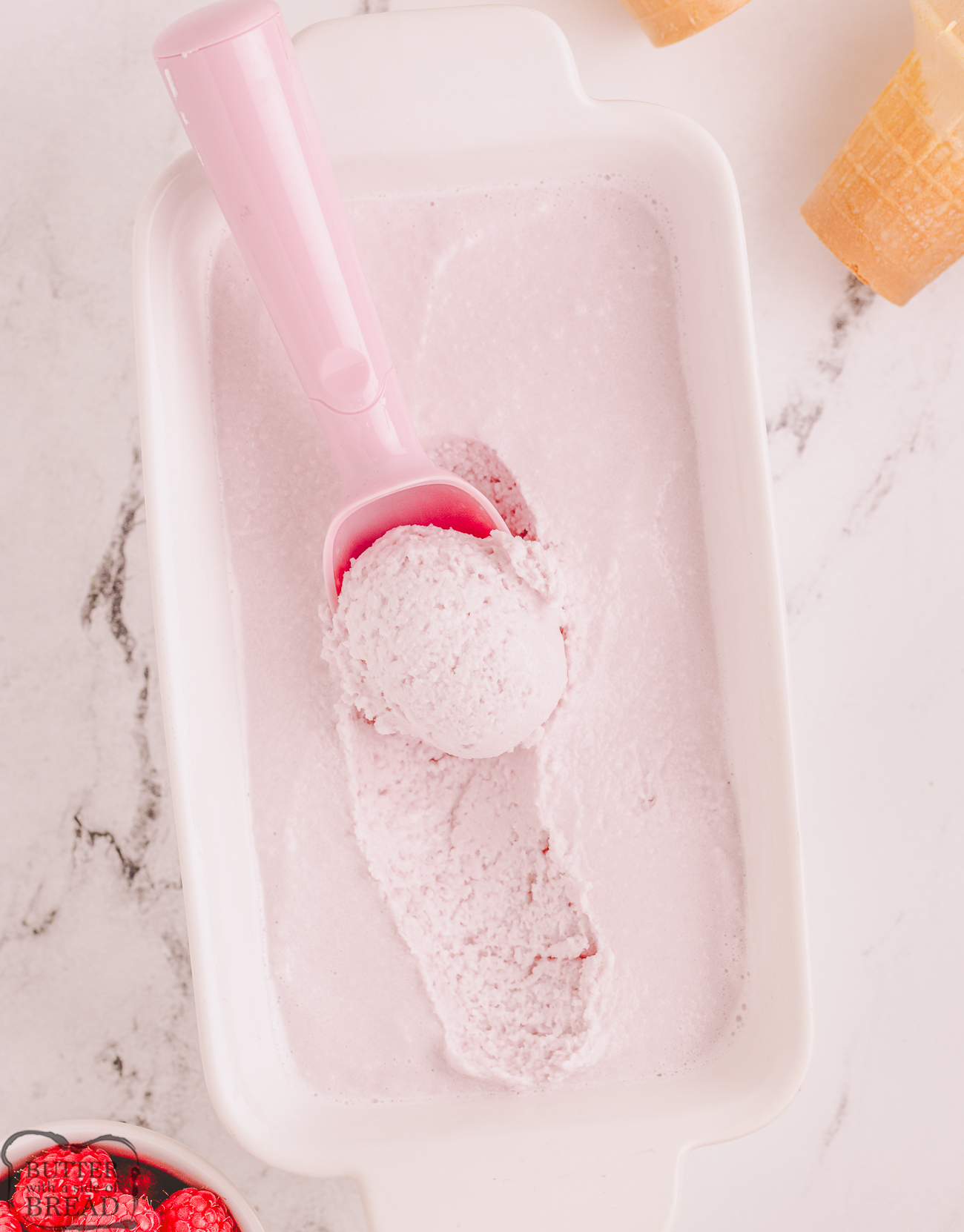 scooping raspberry sherbet from a pan