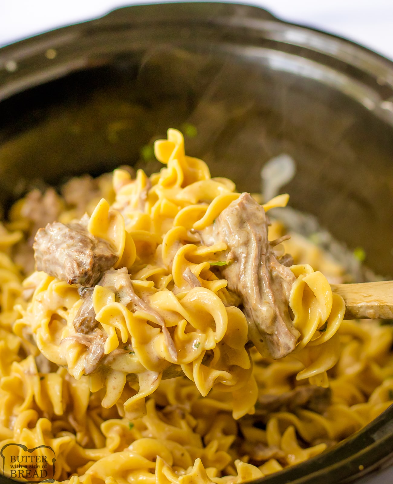 scooping beef stroganoff out of a slow cooker