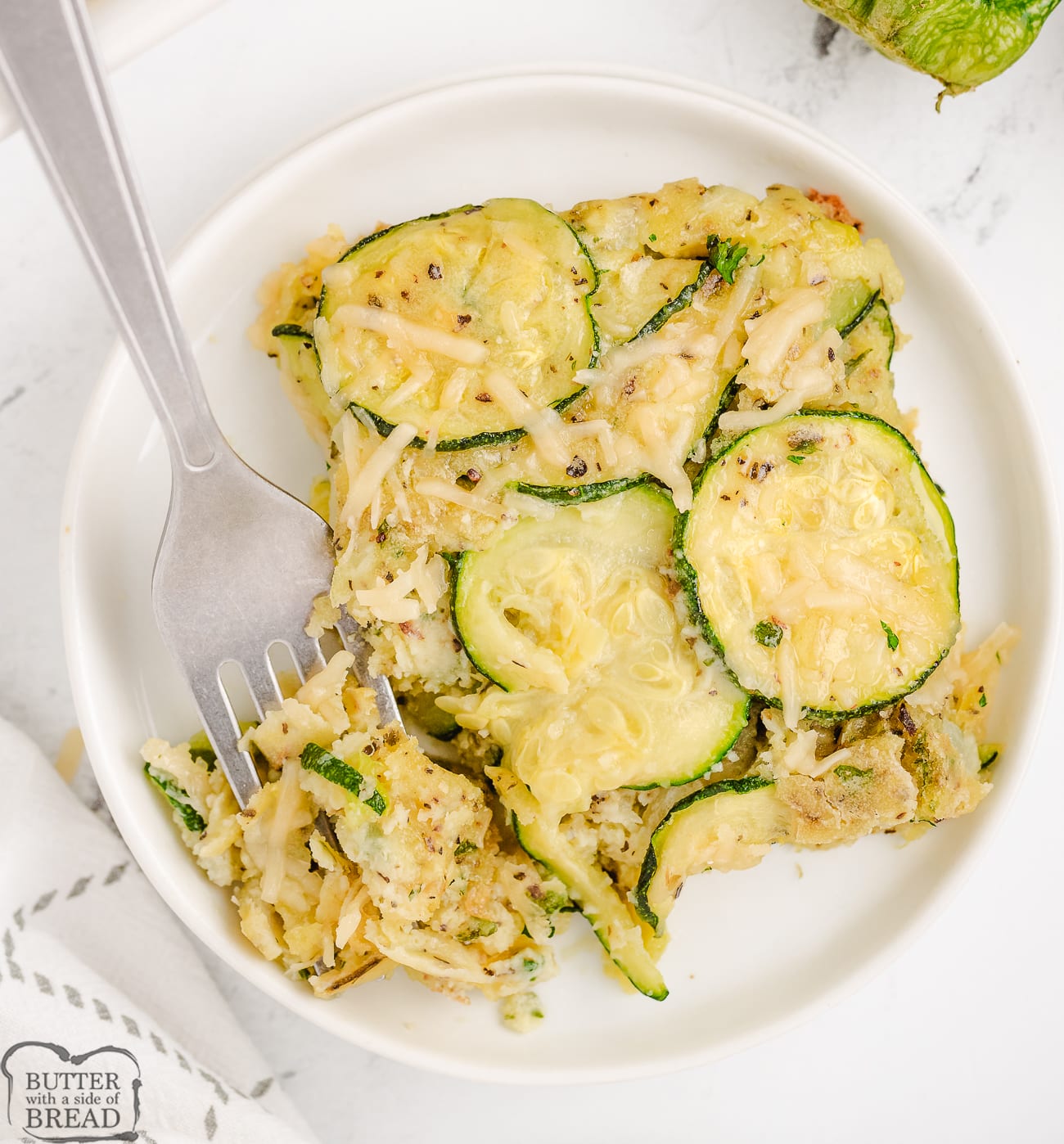 a piece of zucchini Parmesan casserole served on a white plate with a fork